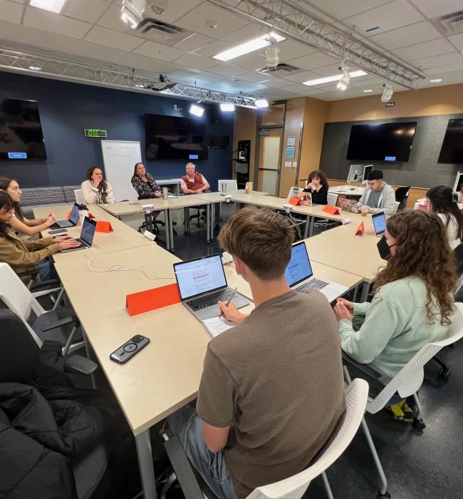 students sitting around desks during panel interview