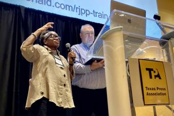 two people speaking into microphone behind podium presenting research